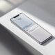 Google Pixel 9 Pro smartphone resting flat on a pale grey concrete surface at a 45-degree angle, screen displaying the Gemini app interface with a clean chat thread visible, soft natural window light from the left casting long diffused shadows, shallow depth of field with sharp focus on the screen, realistic glass and metal reflections, no hands, no people, no text overlays, no watermark, photorealistic, 16:9
