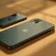 iPhone 11 Pro in midnight green resting slightly out of focus in the background on a warm beige surface, with a newer iPhone 17 Pro in sharp focus in the foreground on the same surface, soft cinematic side lighting from the left, subtle directional shadows, no people, no hands, no text, no watermark, photorealistic, 16:9