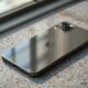 iPhone 18 resting face-up on a warm grey concrete surface, front camera area and Dynamic Island visible from directly above at a slight angle, 50mm lens, soft natural window light from the left, subtle glass reflections, no hands, no people, no text, no watermark, sharp focus, photorealistic, 16:9